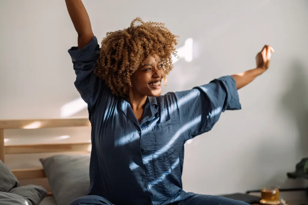 portrait of a happy woman waking up and stretching in bed